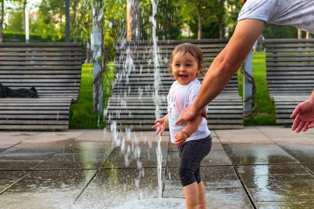 Small child playing in water fountain